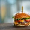 Mouthwatering cheeseburger with fresh tomatoes and lettuce on a wooden surface.